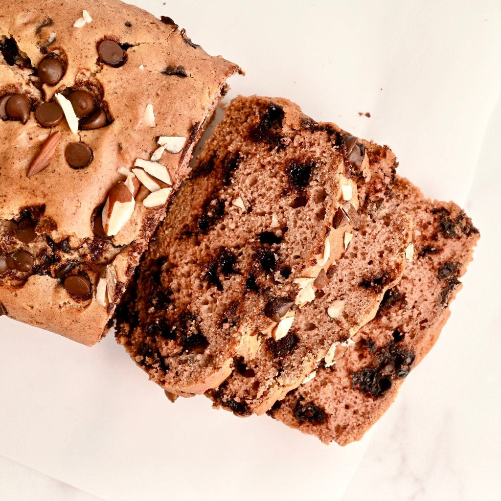 A freshly baked loaf of chocolate chip bread topped with sliced almonds