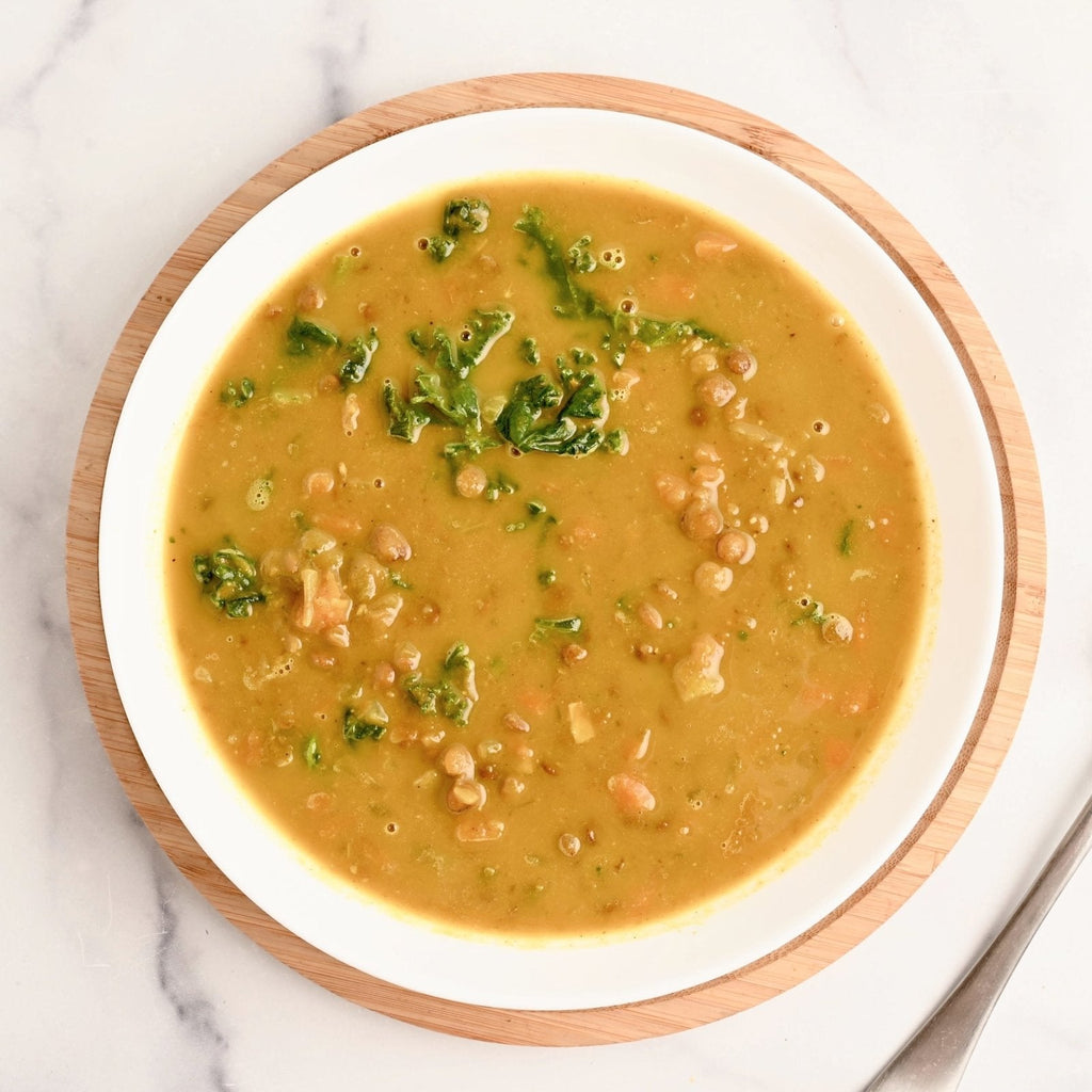 One big soup bowl filled with turmeric lentil soup with fresh kale leaves mixed in