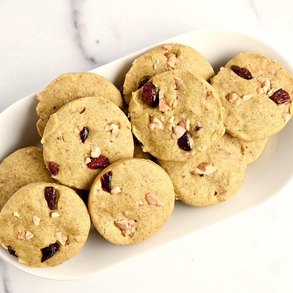 A white ceramic plate with ten homemade pistachio cookies