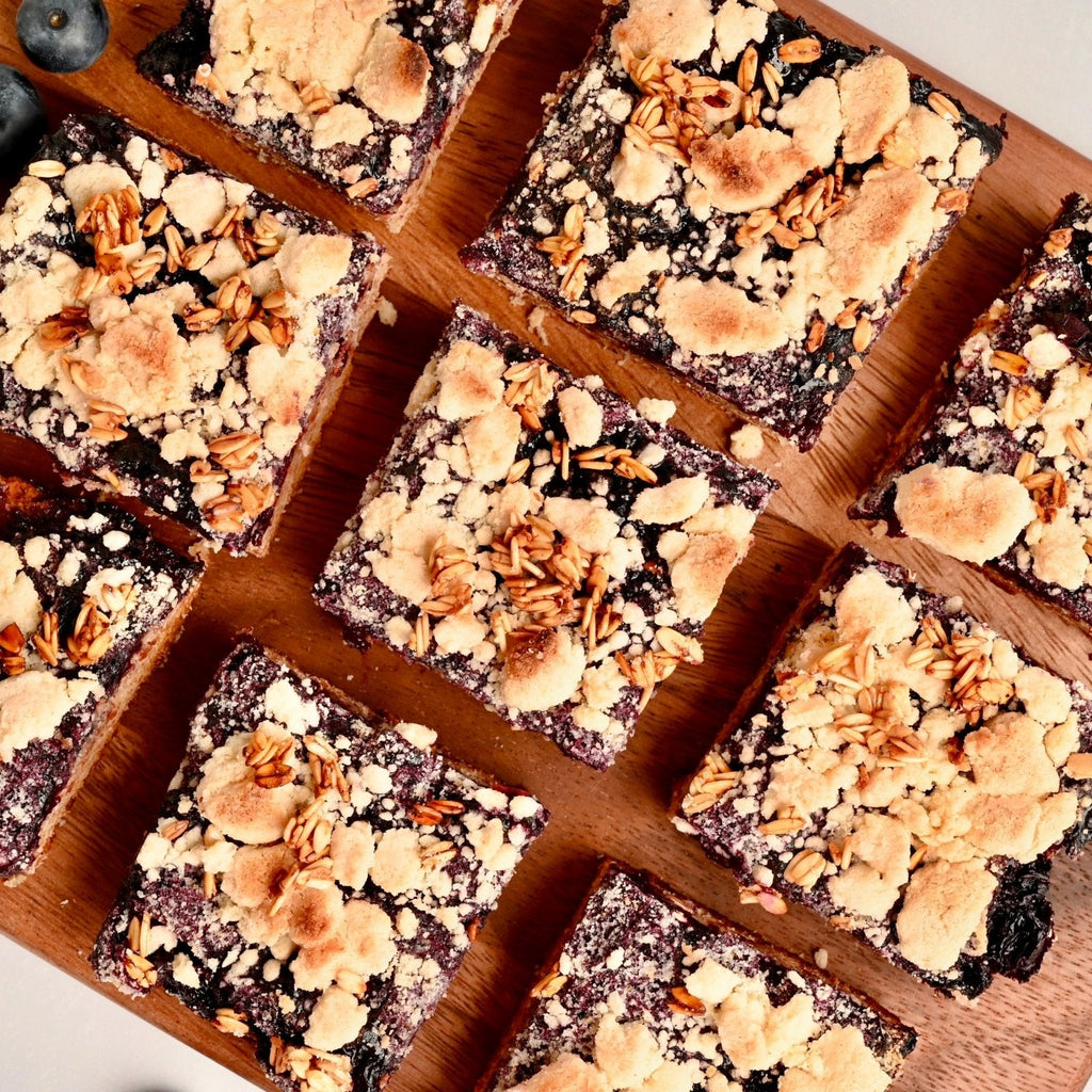 Brown cutting board covered in hand cut squares of homemade Blueberry Bars