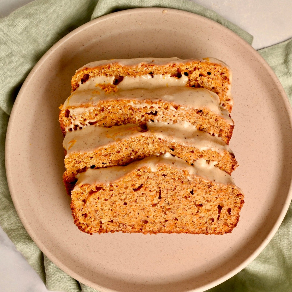 A plate with sliced homemade carrot cake topped with a drizzle of homemade cashew frosting